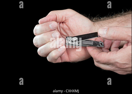 Les garnitures d'un homme ses ongles à l'aide d'une paire de métallique coupe-ongles. Banque D'Images