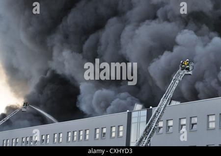 Les pompiers éteignent un incendie qui fait rage dans un entrepôt. Banque D'Images