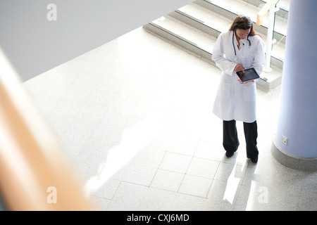 Female doctor standing in corridor à l'aide d'ipad Banque D'Images