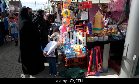 Les femmes musulmanes en burqas contre l'achat de jouets au marché de la rue avec leurs enfants Walthamstow East London UK KATHY DEWITT Banque D'Images