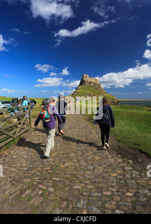 Les visiteurs à marcher en direction de Château de Lindisfarne, Holy Island. Banque D'Images