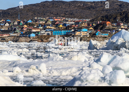 Bâtiments colorés de Ilulissat s'asseoir sur le bord de la ville de glace du port et étouffé se reflètent dans l'eau entre la glace bits. Banque D'Images