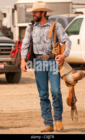 Cowboy bronc rider portant sa selle pour l'arène de rodéo, Bruneau, California, USA Banque D'Images