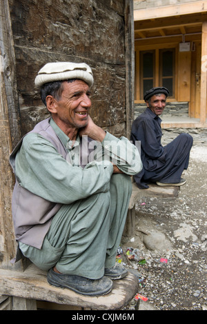 Les hommes accroupis sur un Kalash corniche en bois dans le village de Balanguru, vallée de Rumbur, Chitral, Khyber-Pakhtunkhwa, Pakistan Banque D'Images