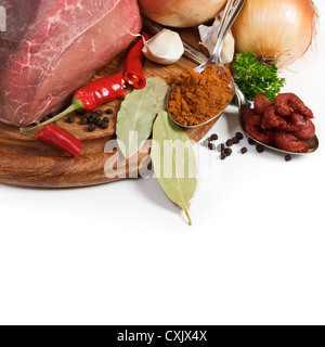 La viande et les ingrédients pour goulash sur planche, close-up, fond blanc Banque D'Images