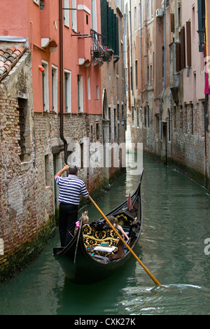 Gondole Gondolier avec passant le long d'un petit canal à Venise, Italie Banque D'Images