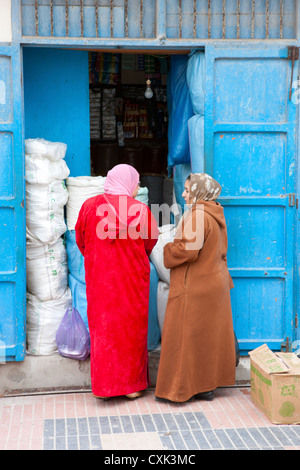 Les femmes marocaines en vêtements traditionnels par l'entrée de shop à Essaouira, Maroc Banque D'Images