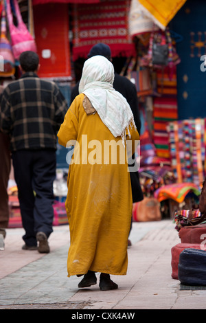 Femme en djellaba walking in market, Essaouira, Maroc Banque D'Images