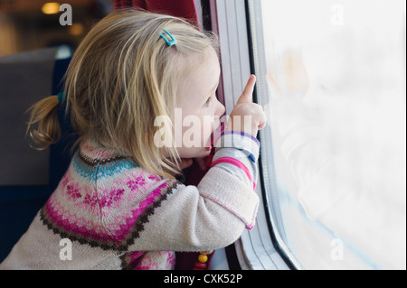 Petite fille à l'aide de sucette et à la fenêtre du train, Banque D'Images