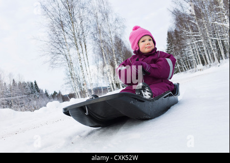 Petite fille sur un traîneau en hiver Banque D'Images