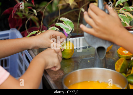 Petite fille en appuyant sur le jus d'Orange à Bangkok Banque D'Images