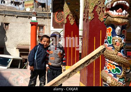 L'Inde, Ladakh, Leh, 2 garçons en face de petit temple bouddhiste coloré avec dragon figure et Leh Palace en arrière-plan Banque D'Images