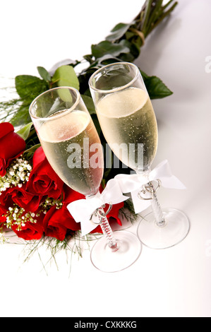 Un bouquet de roses rouges et de remorquage de champange flûtes ou verres de brunissage avec champagne sur fond blanc Banque D'Images