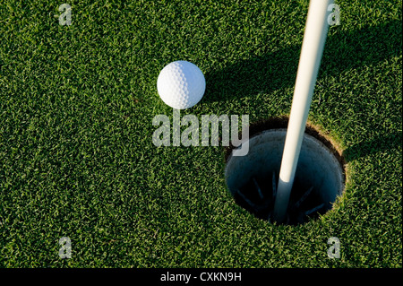 Une balle de golf blanche près du trou d'un vert de golf ou cours Banque D'Images