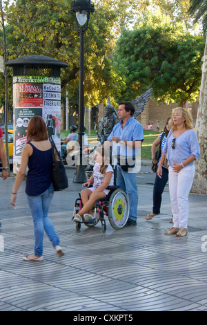 Les parents avec leur fille handicapée en fauteuil roulant dans les rues de Las Ramblas à Barcelone, Espagne, Europe Banque D'Images