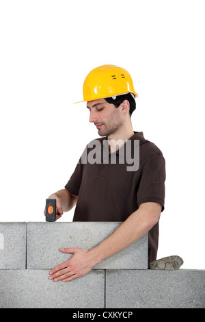 Mason en utilisant un marteau pour régler brick wall Banque D'Images