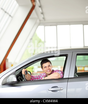 Heureux homme assis dans sa voiture, et la tenue d'une clé de voiture Banque D'Images