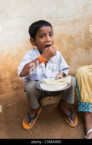 Basse caste indien boy eating dosa pour le petit-déjeuner dans une rue. L'Andhra Pradesh, Inde Banque D'Images