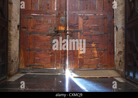 Lumière brillant à travers de grandes portes en bois à l'intérieur de la cathédrale de Valence, en Espagne. Banque D'Images