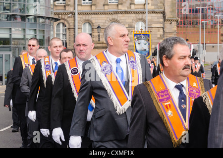 Nombre d'orangistes vêtu du costume traditionnel 'Orange sash' comme ils marchent sur une route pendant une parade de l'ordre d'Orange Banque D'Images