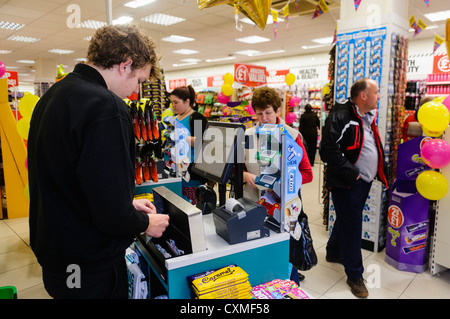 Les clients sont servis à la caisse dans un magasin Poundland. Banque D'Images