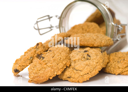 Des délicieux cookies à l'avoine et aux raisins s'échappant d'un récipient en verre Banque D'Images