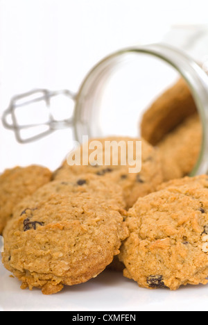 Des délicieux cookies à l'avoine et aux raisins s'échappant d'un récipient en verre Banque D'Images