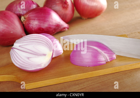 Couper les oignons rouges sur la planche à découper en bois (Selective Focus, Focus sur l'oignon coupé et le couteau) Banque D'Images