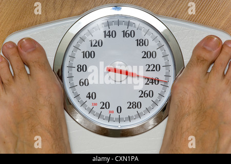L'homme lourd sur l'échelle avec grand cadran pesant 230 livres, thème de suivre un régime ou de perdre du poids Banque D'Images