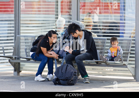 Jeune couple avec enfant s'asseoir sur le banc de la plate-forme de la gare de petit garçon souffle des bulles de savon, principale gare ferroviaire de Heilbronn Banque D'Images