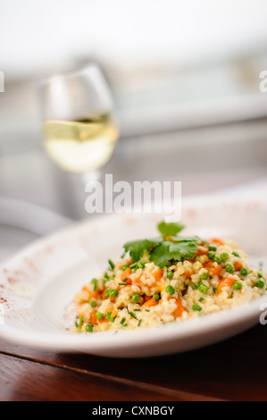 Un bol de risotto fraîchement préparé servi avec un verre de vin blanc sur une table à l'extérieur dans un restaurant à Cornwall Banque D'Images