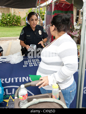 Les jeunes hispaniques policière parle de femme à Austin Police Department kiosque de recrutement à un festival de l'église en plein air Banque D'Images