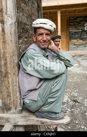 Les hommes accroupis sur un Kalash corniche en bois dans le village de Balanguru, vallée de Rumbur, Chitral, Khyber-Pakhtunkhwa, Pakistan Banque D'Images