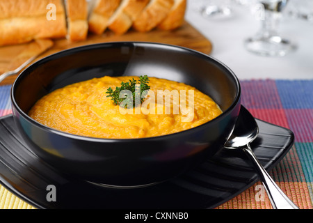 Tomate carotte crème soupe orange au thym garniture dans un bol avec des tranches de pain noir Banque D'Images