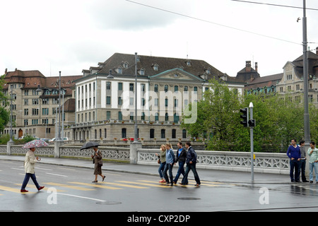 Les personnes qui traversent la route à proximité de pont sur la rivière Limmat à Zurich. A récemment a plu et a été une maison de vacances, donc moins de personnes autour. Banque D'Images