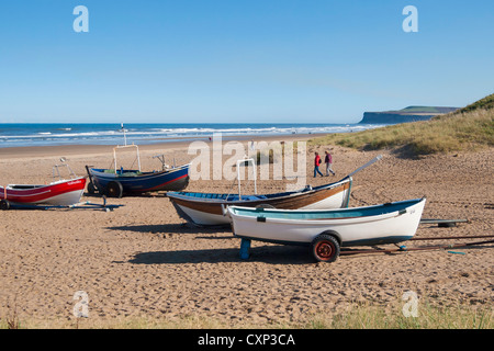 Sur un dimanche après-midi ensoleillée d'automne deux femmes à pied par les bateaux de pêche sur la plage de Marske Banque D'Images