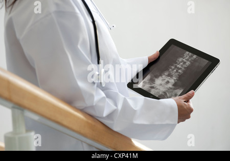 Femme médecin à la recherche de x-ray sur ipad tablet computer Banque D'Images