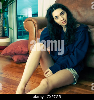 Jeune femme assise sur le sol à la maison Banque D'Images