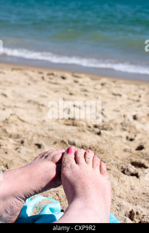 Les pieds couverts de sable sur une plage Banque D'Images