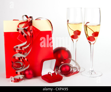 Des cadeaux de Noël sac de papier et boîte de bijoutier avec joints toriques et avec des boules en rouge et verres de champagne sur fond blanc Banque D'Images