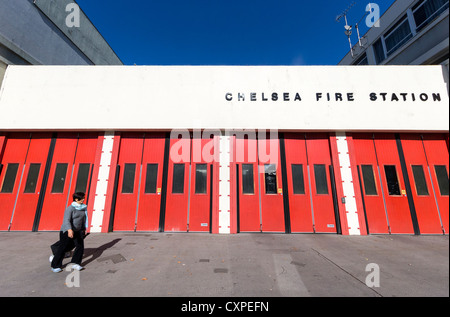 Une femme devant la porte rouge de Chelsea Fire Station in London's Kings Road Banque D'Images