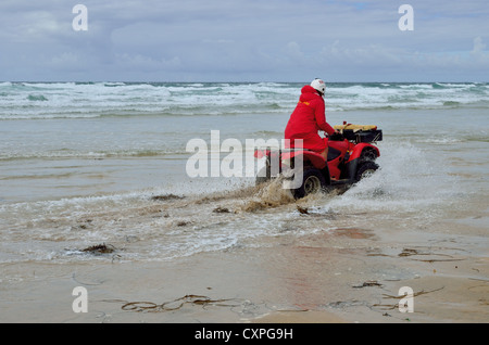 Lifeguard équitation quad à travers les hauts-fonds sur Broad Oak beach, North Cornwall Banque D'Images