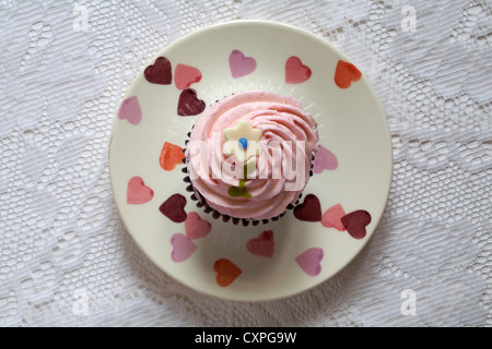 Regardant vers le bas sur fraise cupcake avec Daisy sur haut sur la plaque avec des coeurs sur - d'en haut Banque D'Images