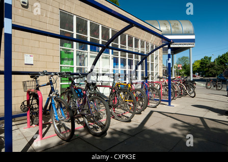 Les vélos garés infiltration en toute sécurité dans une aire de stationnement à l'extérieur d'une gare d'Angleterre. Banque D'Images