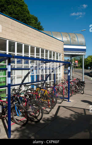 Les vélos garés infiltration en toute sécurité dans une aire de stationnement à l'extérieur d'une gare d'Angleterre. Banque D'Images