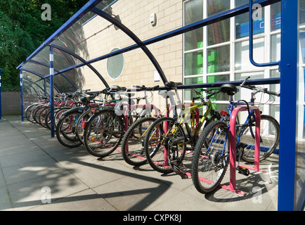 Les vélos garés infiltration en toute sécurité dans une aire de stationnement à l'extérieur d'une gare d'Angleterre. Banque D'Images