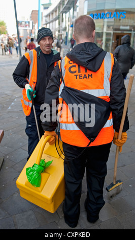 Deux city street cleaners à visibilité élevée jour-glow vestes holding manches. Banque D'Images