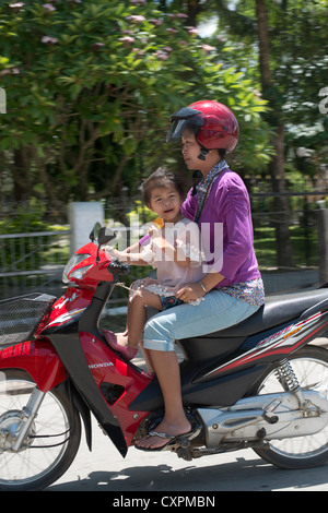 Une mère et son enfant passent sur une moto à Luang Prabang, Laos Banque D'Images