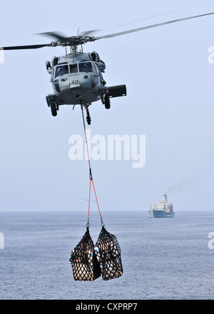MH-60 de l'US Navy Sea Hawk offre de fret vers la cabine de pilotage à bord du navire quai de transport amphibie USS New York au cours d'un ravitaillement en mer le 2 octobre 2012 dans le golfe d'Aden. Banque D'Images