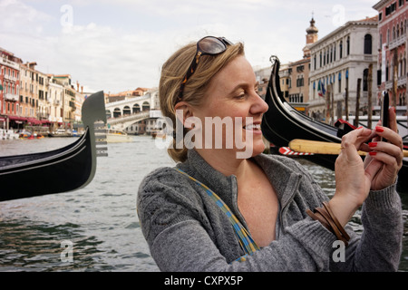Woman taking photo sur téléphone mobile (iPhone) Grand Canal, Venise, Italie Banque D'Images